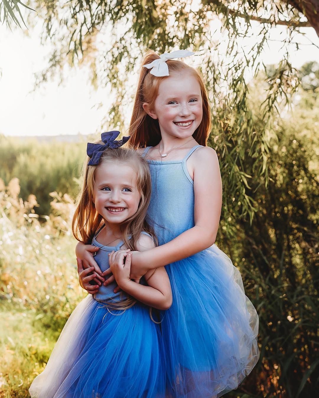 Two sisters in blue tutus hugging
