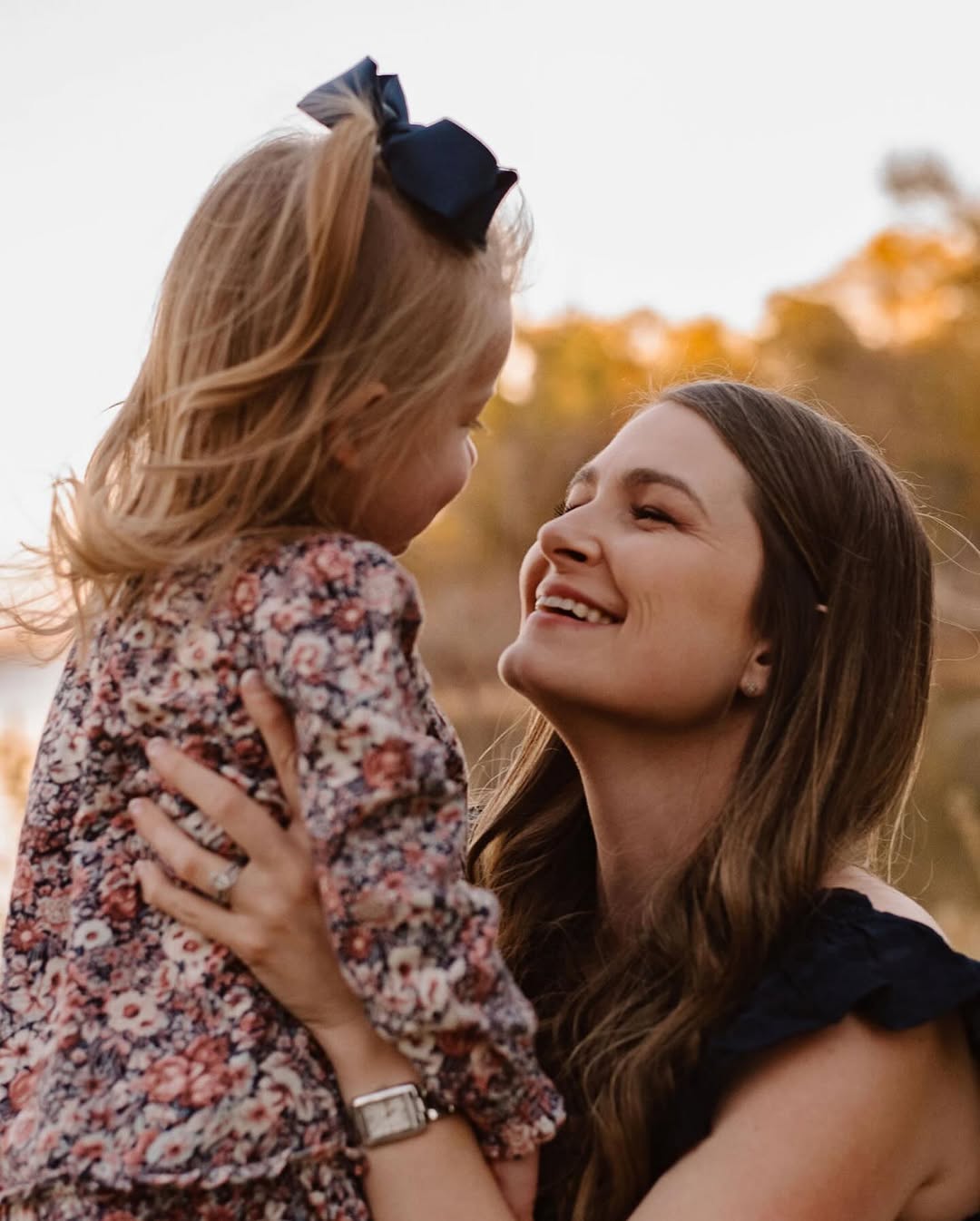 Mom laughing with her daughter in her arms