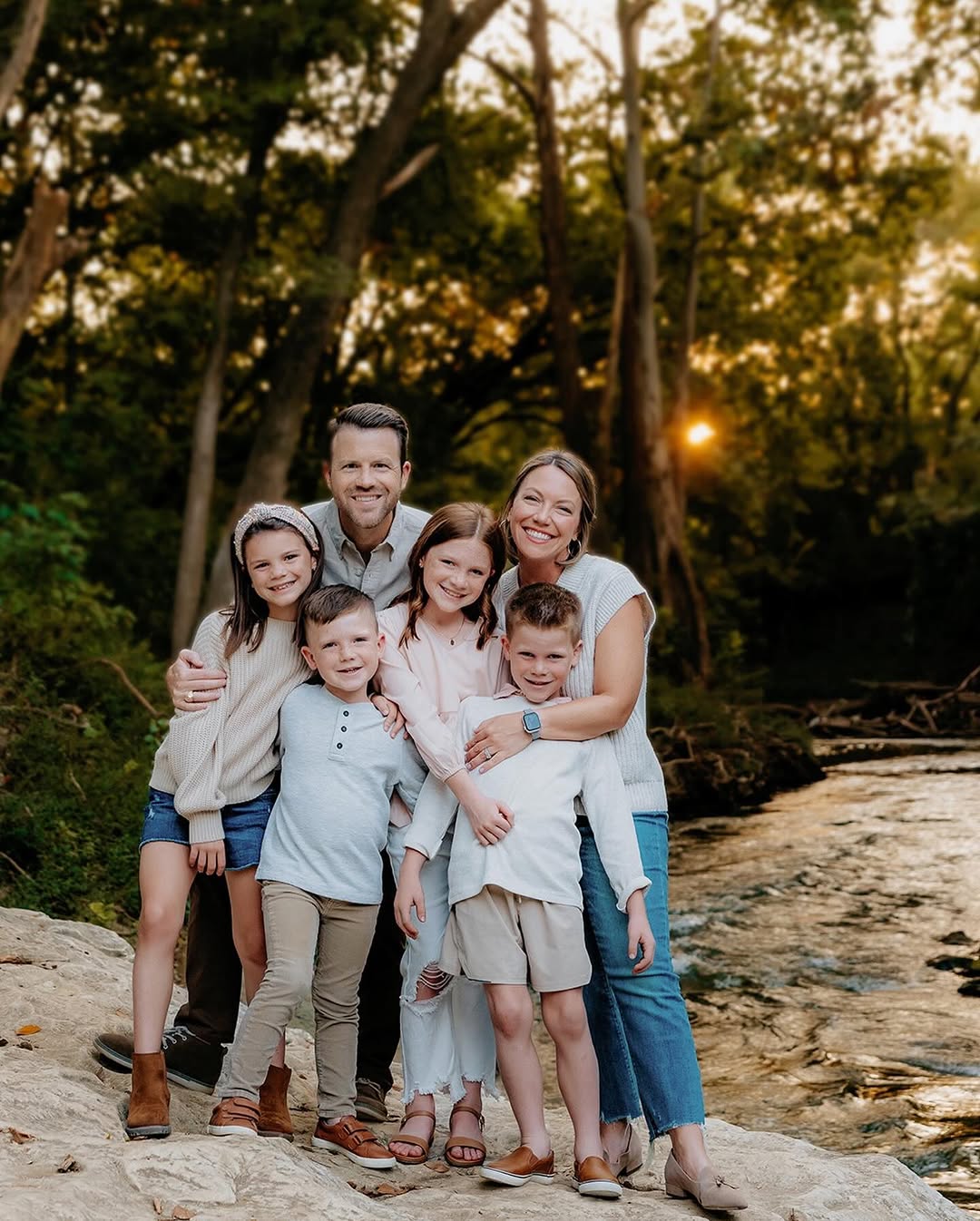 Family of six by a creek at sunset